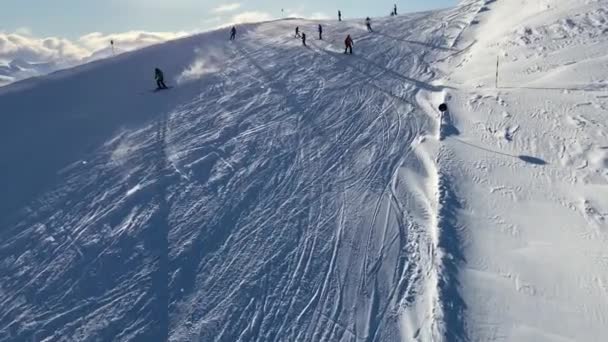 Az emberek síelnek a havas lejtőn a síközpontban a hegyekben — Stock videók