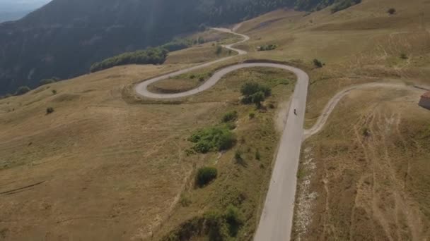 Aerial view of a man driving a motorbike on a mountain road — Stock Video