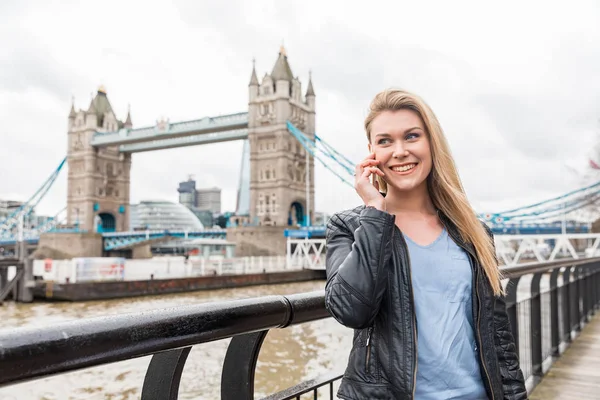 Een vrouw aan de telefoon in Londen bij Tower Bridge. — Stockfoto