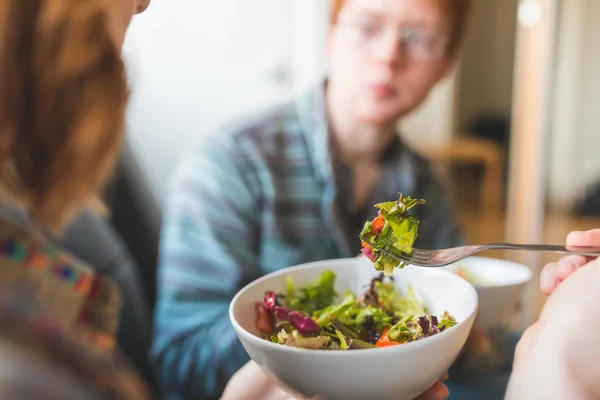 Couple eating healty salad at home on the sofa — Stock Photo, Image