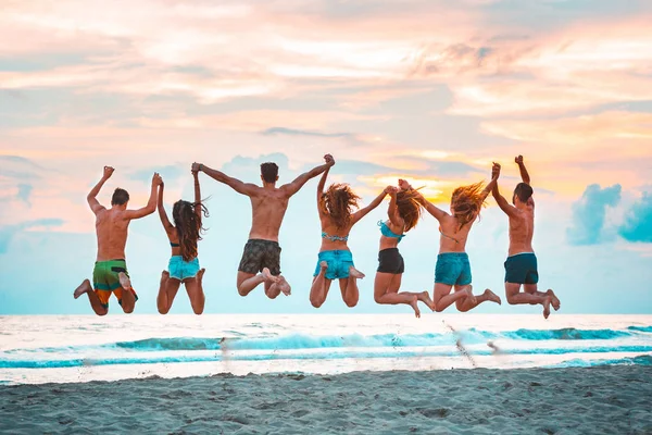 Heureux amis qui sautent sur la plage — Photo