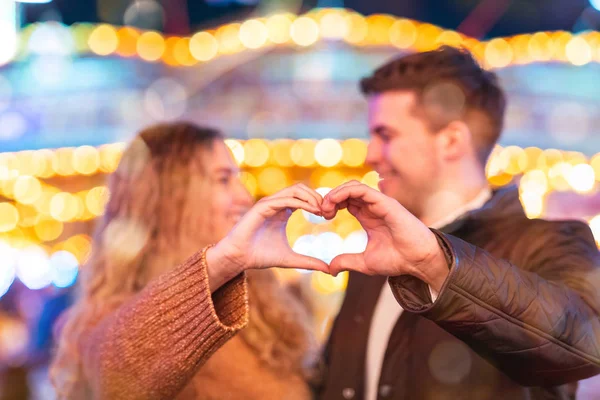 Ευτυχισμένο ζευγάρι στην αγάπη στο λούνα παρκ κάνοντας σχήμα καρδιάς με h — Φωτογραφία Αρχείου