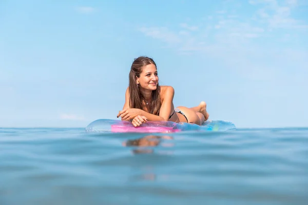 Beautiful girl at seaside relaxing on an inflatable mattress — ストック写真