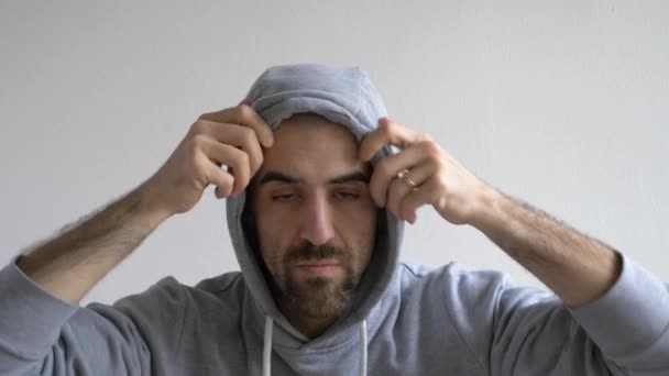 Funny man pulling down hoodie and showing shaven head, slow motion — Stock Video