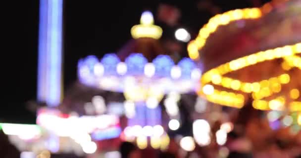 Blurred amusement park background at night with carousel spinning and attract — Stock Video