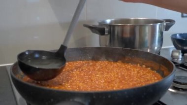 Domates soslu risotto pilavı pişirmek - kadın eli ve tava yakın