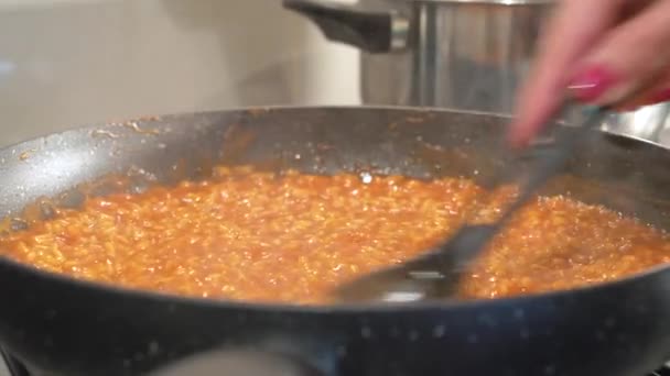 Risotto-Reis mit Tomatensauce kochen - weibliche Hände und Pfanne in Nahaufnahme — Stockvideo