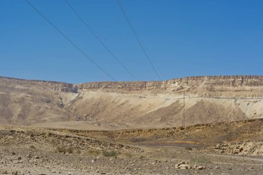 İsrail 'deki Negev Çölü' nün Rocky tepelerinin sonsuz ıssızlığı. Orta Doğu 'nun manzarasındaki sütunlar üzerindeki elektrik hatları