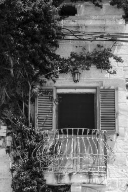 Geleneksel Malta pencereli bir bina. Taze çiçeklerle süslenmiş. Siyah beyaz resim 