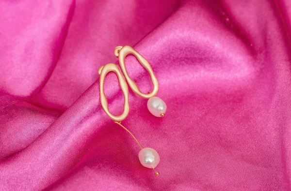 Modern Asymmetrical Golden Earrings Pearl Beads Pink Silk Background — Stock Photo, Image