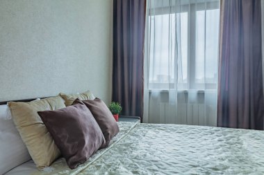 Yatakta yastık ve konforlu yatak odasında bej renkli komodin.