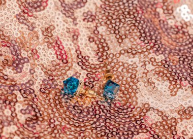 Altın arkaplanda mavi değerli taşları olan bir çift modern altın küpe