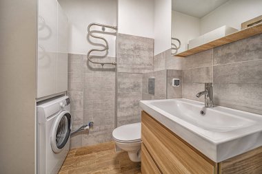 Tuvaleti, lavabosu, aynası, çamaşır makinesi ve çağdaş iç tasarımı olan küçük modern banyo.