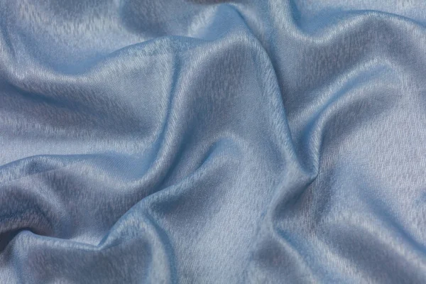 Creased blue curved cloth material fragment with swirl as fabric background texture