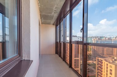Modern apartmanın küçük balkon iç mimarisi bej döşemeli döşemeler ve siyah pencere çerçeveleri