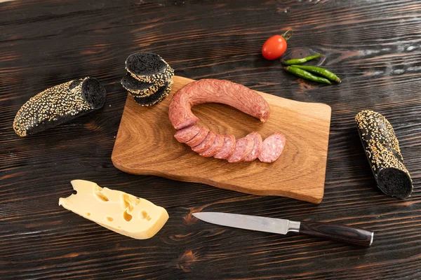 Нарізаний сир, ковбаса і хліб на дерев'яній обробній дошці — стокове фото