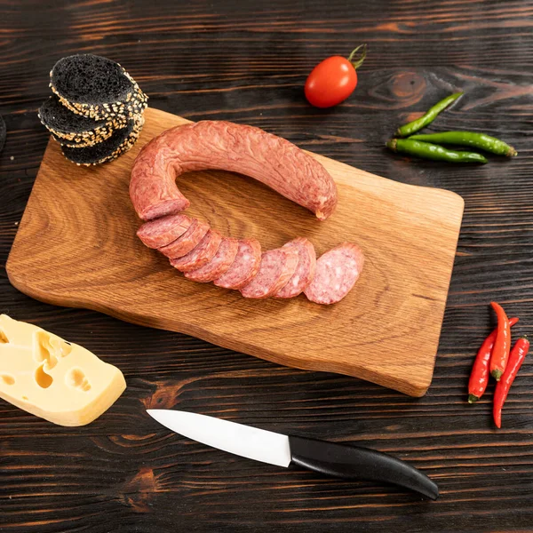 Diiris keju, sosis dan roti di papan potong kayu — Stok Foto