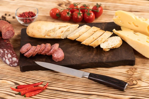Krájený sýr, klobása a chleba na dřevěné řezací desce — Stock fotografie