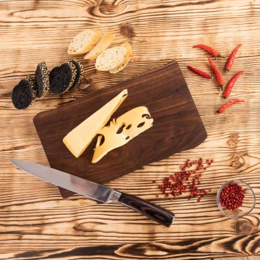 Tahta kesme tahtasında dilimlenmiş peynir, sosis ve ekmek.