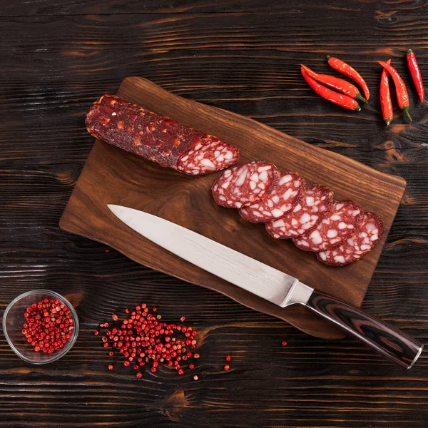 Sosis daging merah segar yang diiris dengan pisau di papan potong kayu — Stok Foto