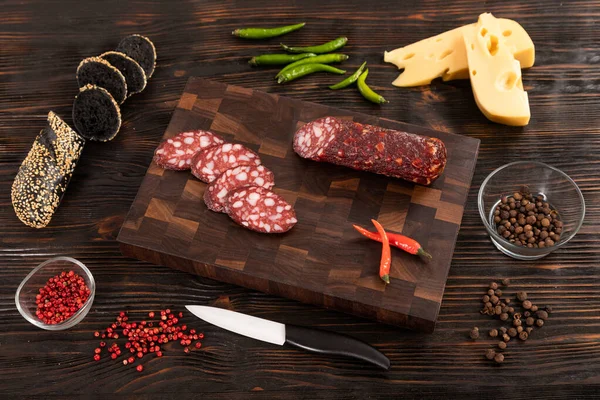 Diiris keju, sosis dan roti di papan potong kayu — Stok Foto