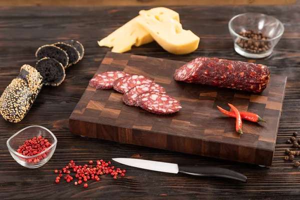 Sliced cheese, sausage and bread on a wooden cutting board — Stock Photo, Image