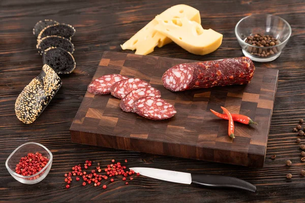 Sliced cheese, sausage and bread on a wooden cutting board — Stock Photo, Image