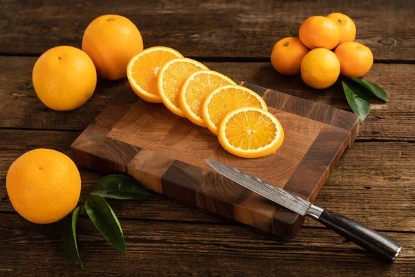 Naranjas anaranjadas cortadas en una tabla de cortar madera . — Foto de Stock