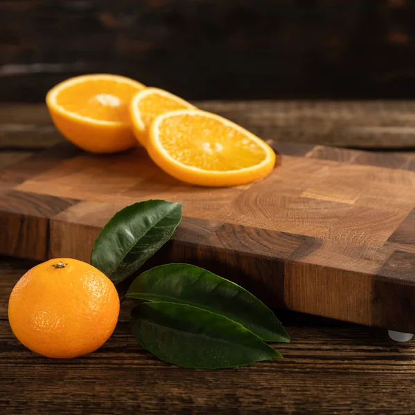 Naranjas anaranjadas cortadas en una tabla de cortar madera . — Foto de Stock