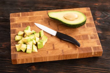 Avokado küp ile dilimlenmiş, tahta kesme tahtasındaki bıçakla.