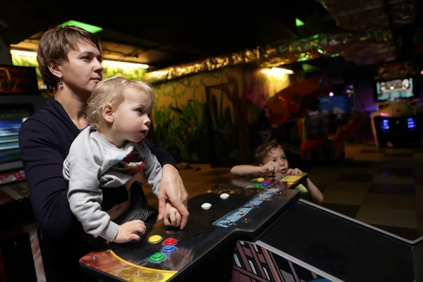 Mãe com seus filhos jogando nas máquinas caça-níqueis — Fotografia de Stock