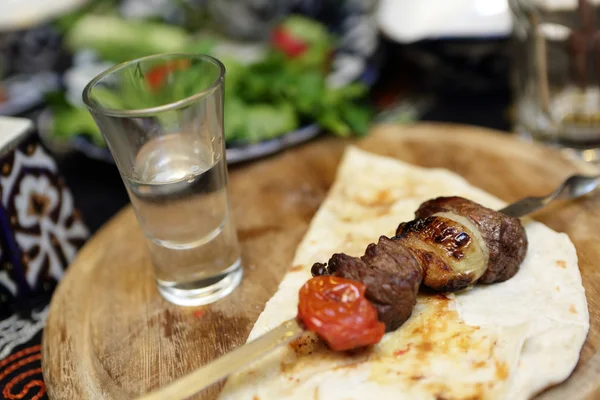 Kebab on skewers and glass of vodka — Stock Photo, Image