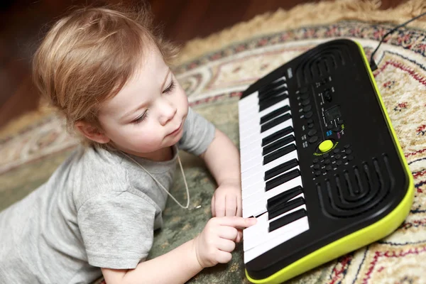 Junge liegt und spielt auf Synthesizer — Stockfoto