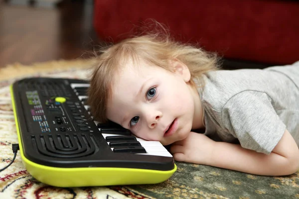 Детская ложь и игра на синтезаторе — стоковое фото