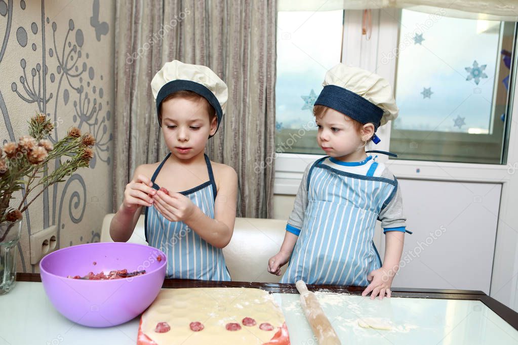 Two serious children mold dumplings