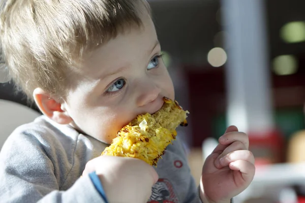 Menino comendo milho espiga grelhada — Fotografia de Stock