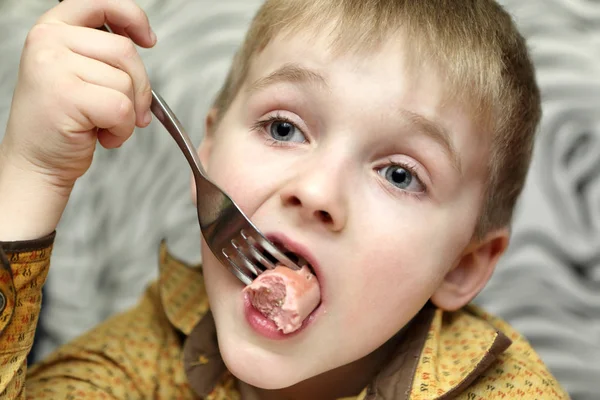 Pensive child eating sausage — Stock Photo, Image