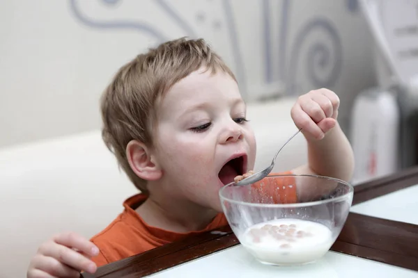 Menino comendo flocos no leite — Fotografia de Stock