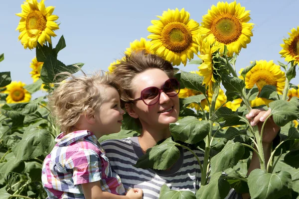 Mutter mit Sohn inmitten von Sonnenblumen — Stockfoto