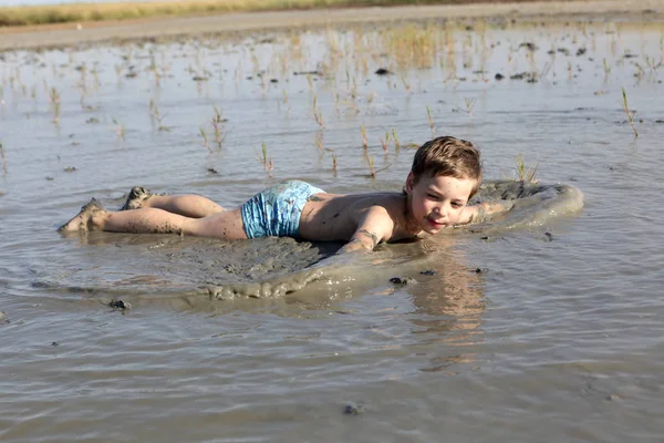 Kid lying in healing mud — Stock Photo, Image