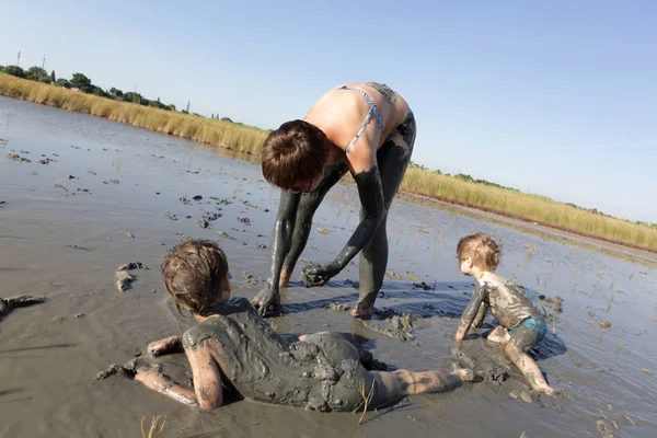Mulher com dois filhos na lama de cura — Fotografia de Stock