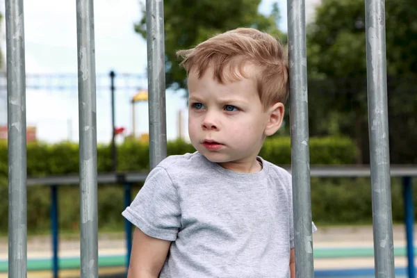 Serious boy on fence background — Stock Photo, Image