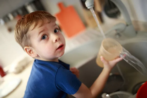 Мальчик моет посуду — стоковое фото