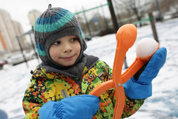 Chlapec hrající s sněhová koule maker — Stock fotografie