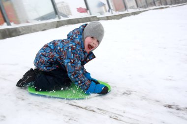 Çocuk kar üzerinde rulo