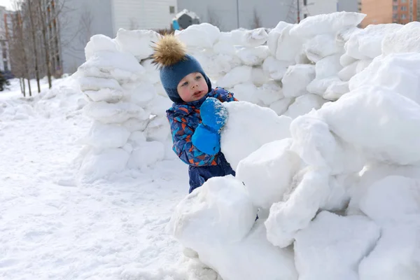 Niño construyendo la fortaleza de nieve — Foto de Stock
