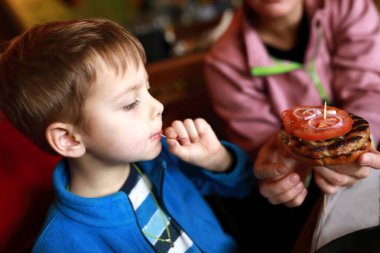 Anne oğlunu hamburgerle besliyor.