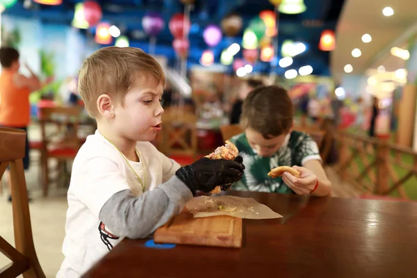 Niño comiendo hamburguesa con queso — Foto de Stock