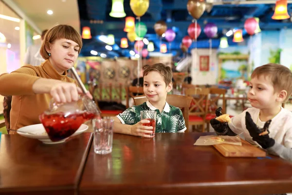 Mother pouring juice to sons