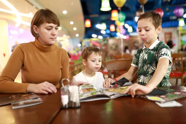 Mother with sons choosing dish in menu — 图库照片